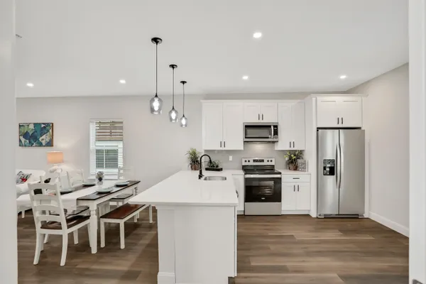 a kitchen with stainless steel appliances kitchen island granite countertop a dining table chairs stove refrigerator and microwave