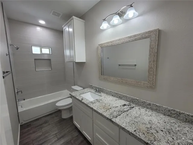 a bathroom with a granite countertop sink a toilet and shower