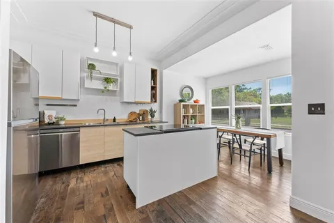 a kitchen with granite countertop a stove top oven a sink a counter space and wooden floor