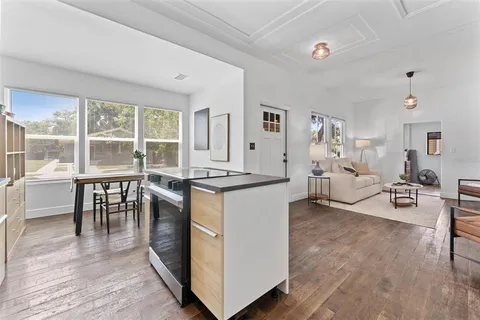 a living room with furniture a large window and wooden floor