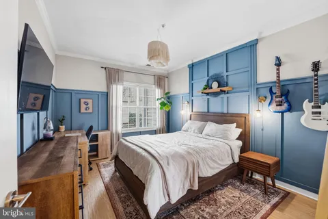 a spacious bedroom with a bed a dresser and wooden floor