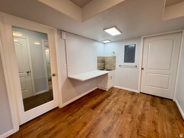665 West State Road Lehi, UT 84043 - Photo 23 of 30 Utility area featuring wood-finish flooring, a white floating desk with pegboard, a stainless steel sink with tiled backsplash, and recessed lighting