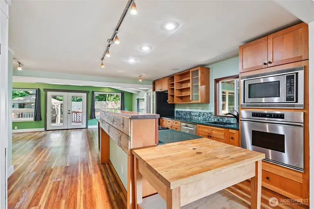 a kitchen with stainless steel appliances granite countertop a stove top oven a sink dishwasher and a microwave oven with cabinets