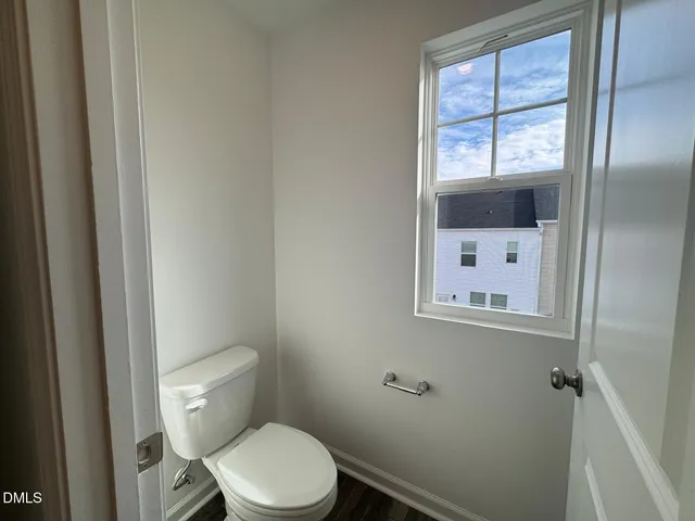 a white toilet sitting next to a window in a bathroom