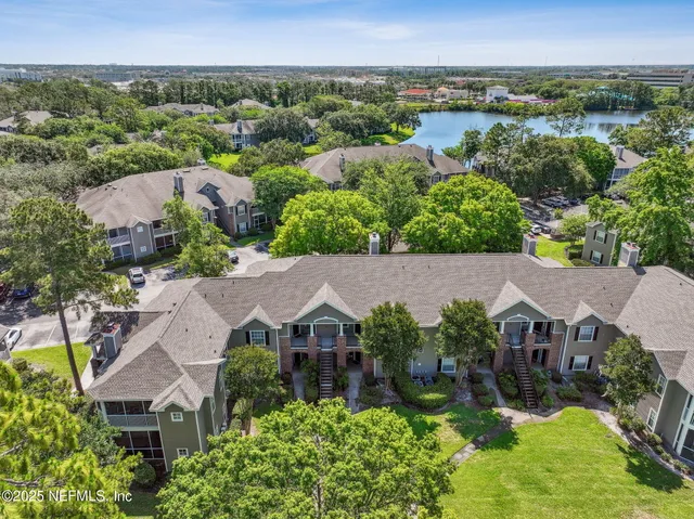 an aerial view of residential houses with outdoor space and lake view in back
