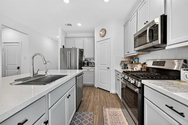a kitchen with stainless steel appliances granite countertop a sink stove microwave and refrigerator