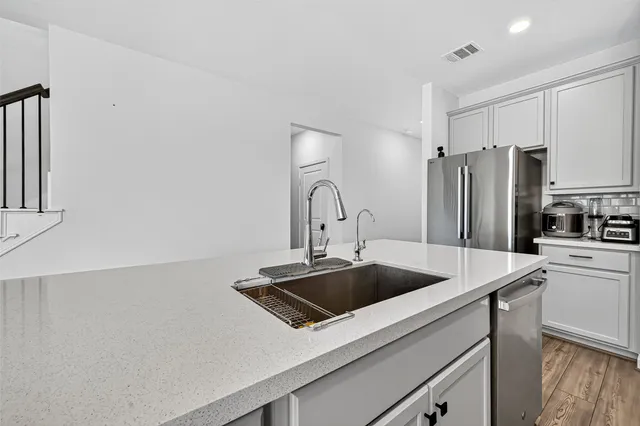 a kitchen with a sink a refrigerator and white cabinets