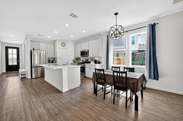 a kitchen with stainless steel appliances kitchen island granite countertop wooden floors and white cabinets