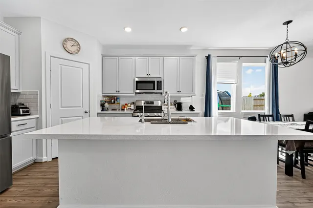 a kitchen with stainless steel appliances a sink a stove a refrigerator cabinets and a window