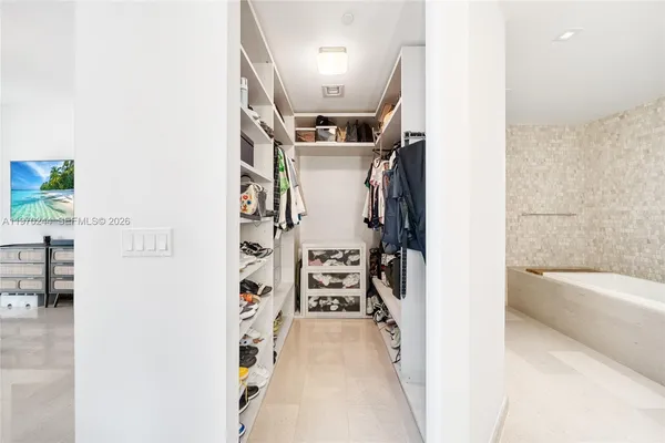 a view of walk in closet with clothes and shoes