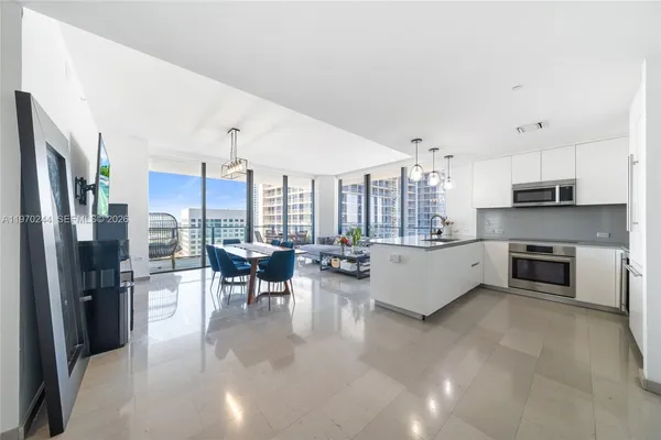 a living room with stainless steel appliances furniture a fireplace and a view of kitchen