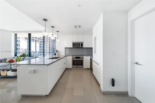 a large white kitchen with cabinets a sink and appliances