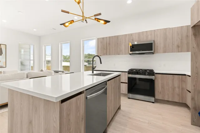 a kitchen with stainless steel appliances a sink a stove a microwave a refrigerator and cabinets