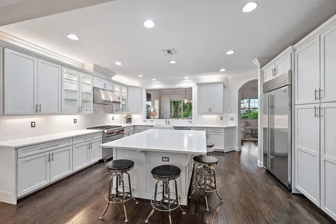 a large kitchen with kitchen island a dining table chairs and white cabinets