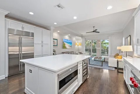 a large kitchen with stainless steel appliances a large center island attached withe living room