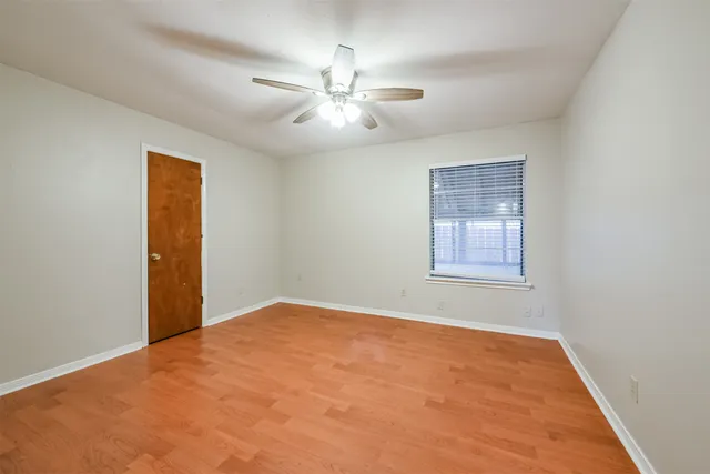 a view of an empty room with chandelier fan and a window