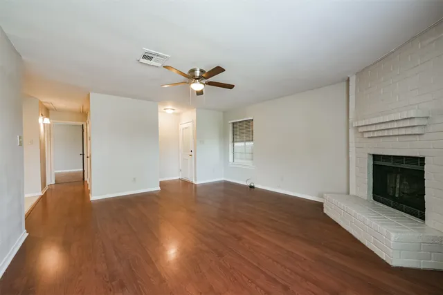 a view of an empty room with wooden floor and a fireplace