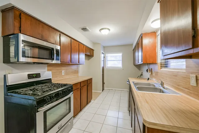 a kitchen that has a sink wooden cabinets and stainless steel appliances