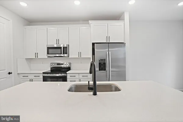 a kitchen with kitchen island a refrigerator sink and stove