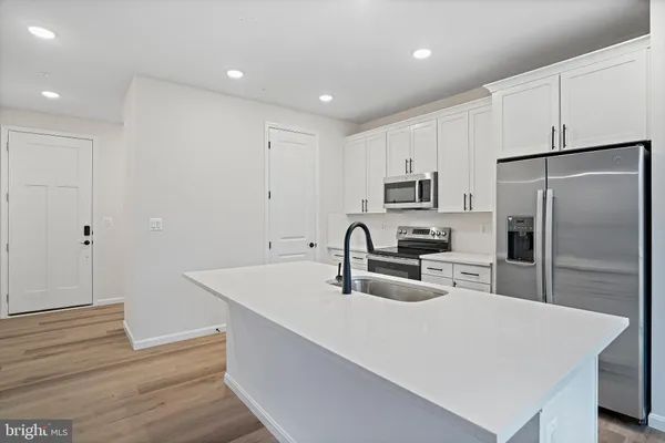 a kitchen with stainless steel appliances a refrigerator sink and white cabinets