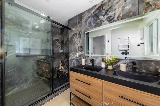 a bathroom with a granite countertop sink a mirror and shower
