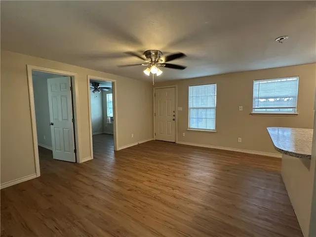 a view of an empty room with window and wooden floor
