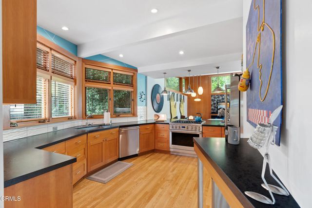 a kitchen with granite countertop a refrigerator a sink a stove and cabinets