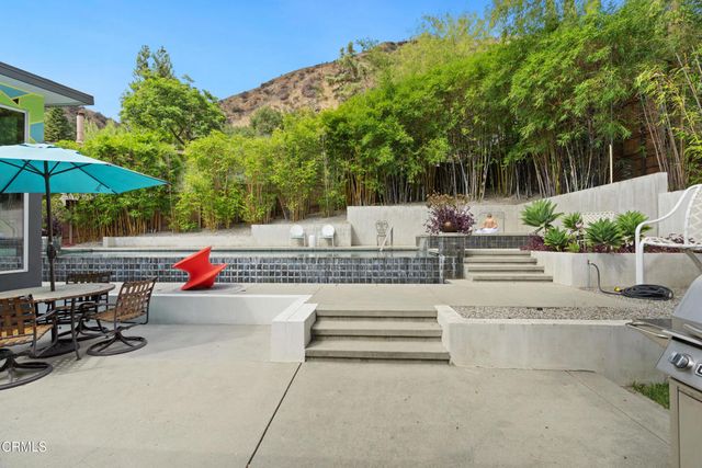 a view of a patio with table and chairs potted plants and a palm tree