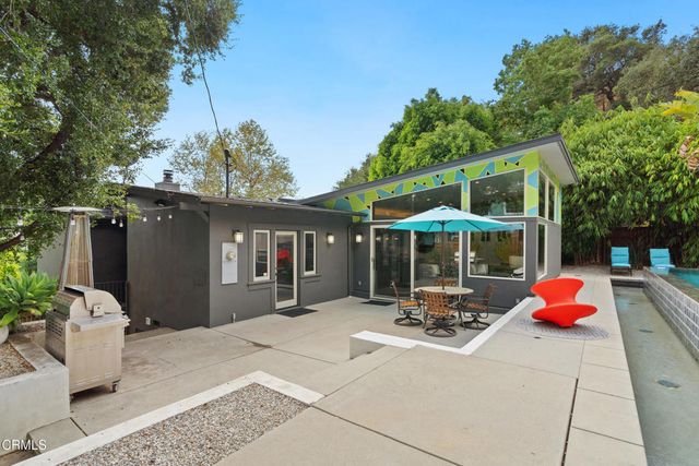 a view of a patio with table and chairs potted plants and a large tree
