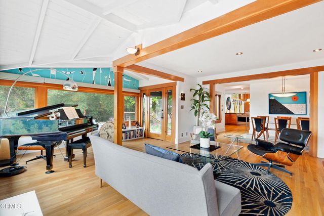 a view of a dining room and livingroom with furniture wooden floor a rug a painting and a chandelier
