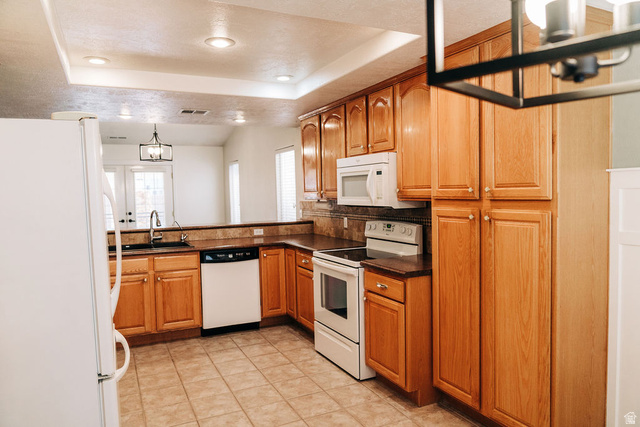 1825 West Mathis Park Place, Unit 40 St. George, UT 84770 - Photo 24 of 28 Kitchen with white appliances, dark countertops, a tray ceiling, wood finish cabinets, and a chandelier