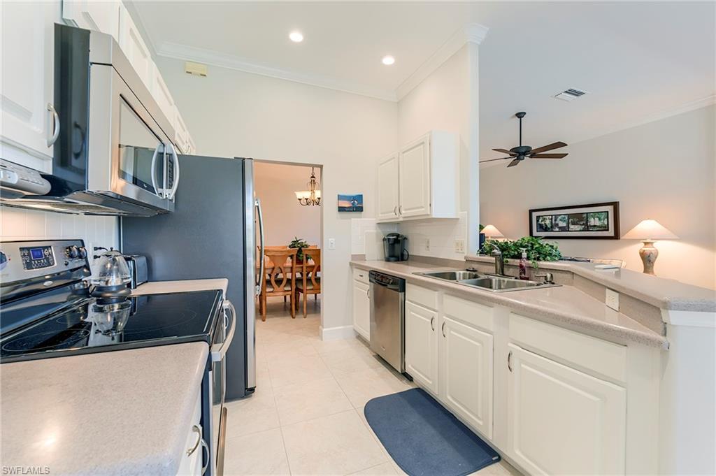 9049 Spring Run Boulevard Estero, FL 34135 - Photo 11 of 36 a kitchen with stainless steel appliances granite countertop a sink stove and refrigerator