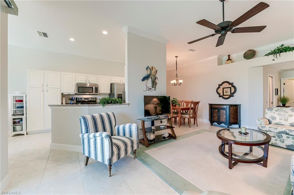 9049 Spring Run Boulevard Estero, FL 34135 - Photo 6 of 36 a living room with furniture kitchen view and a chandelier