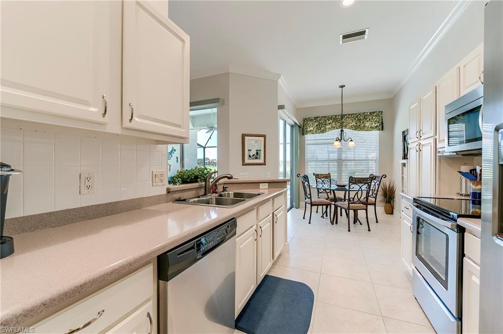 9049 Spring Run Boulevard Estero, FL 34135 - Photo 9 of 36 a kitchen with stainless steel appliances granite countertop a sink a stove and a refrigerator
