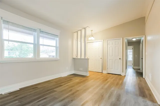 an empty room with wooden floor and windows