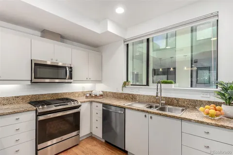 a kitchen with granite countertop a sink stove and cabinets