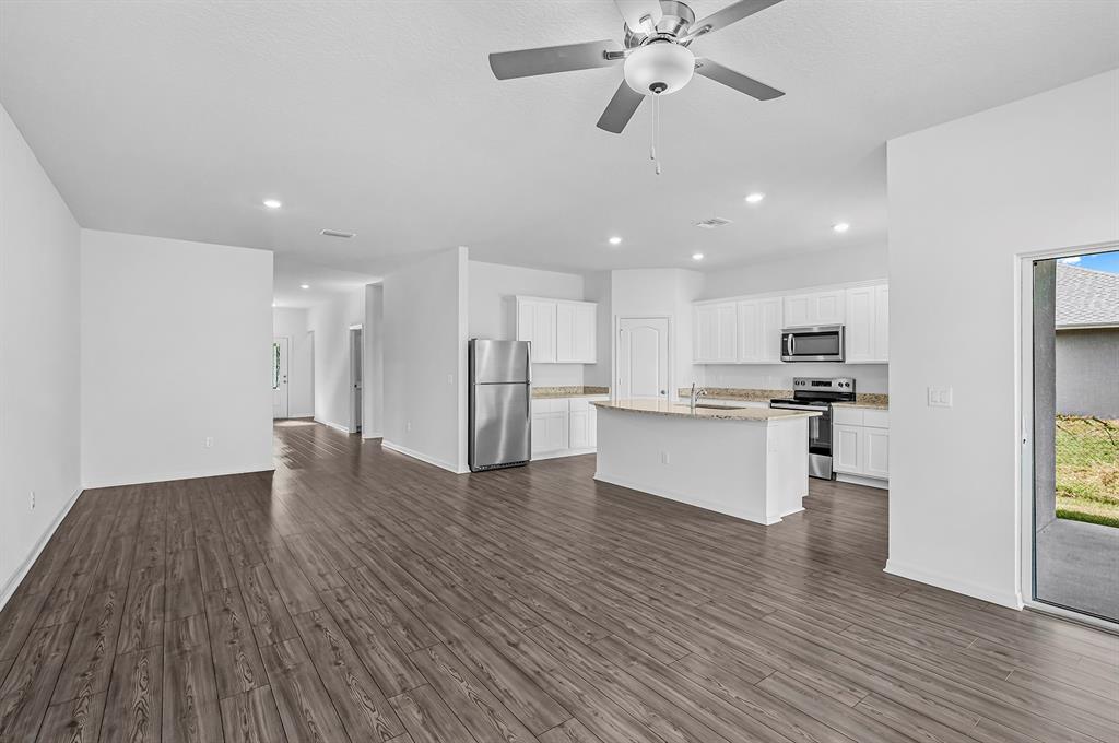 7886 99th Court Vero Beach, FL 32967 - Photo 4 of 18 a view of kitchen with refrigerator microwave and stove with wooden floor