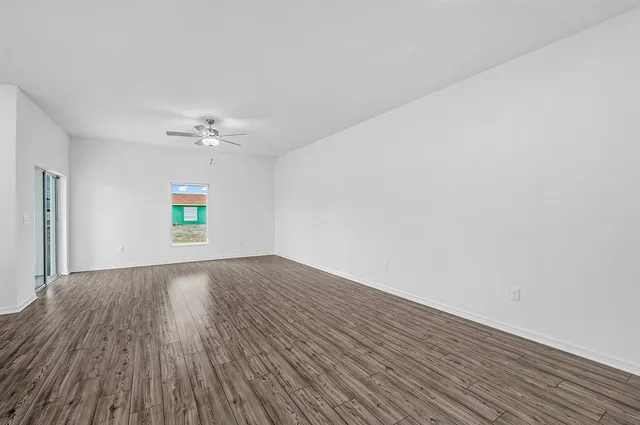 a view of an empty room with wooden floor and window