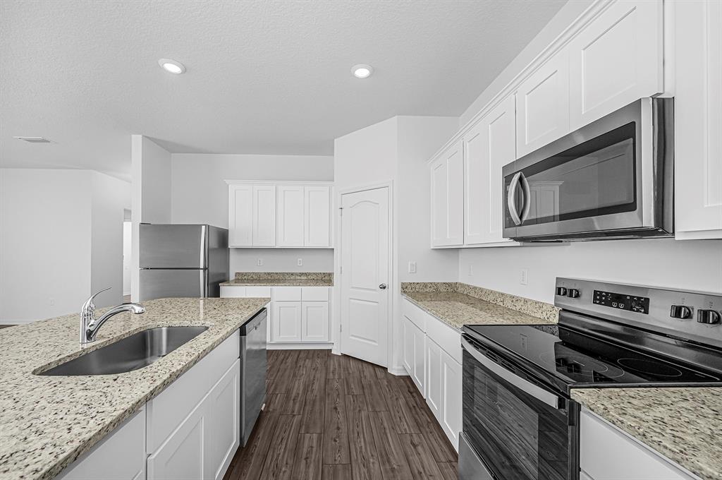 7886 99th Court Vero Beach, FL 32967 - Photo 8 of 18 a kitchen with granite countertop a sink a stove top oven and cabinetry