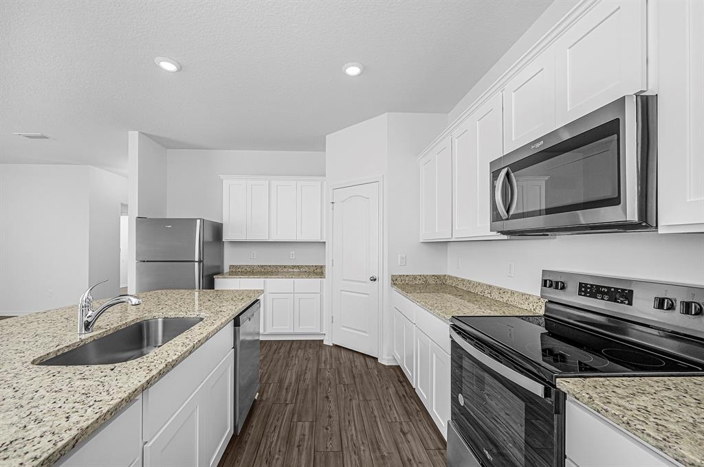 7886 99th Court Vero Beach, FL 32967 - Photo 9 of 18 a kitchen with granite countertop a sink a stove top oven and cabinetry