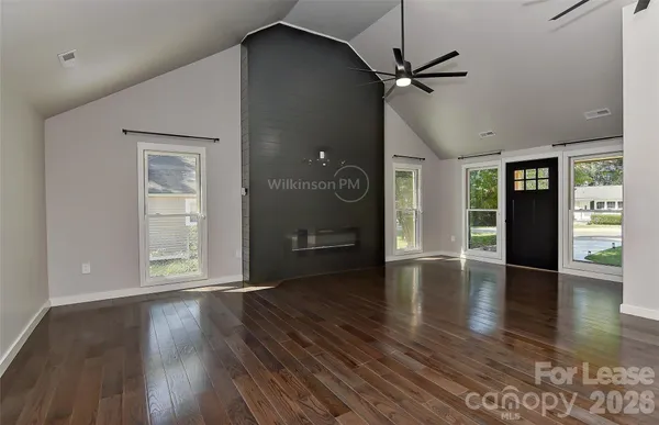 a view of an empty room with a window and wooden floor
