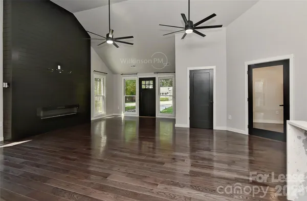 a view of an empty room with wooden floor and a ceiling fan