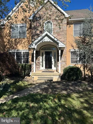 a view of a house with a small yard and large trees