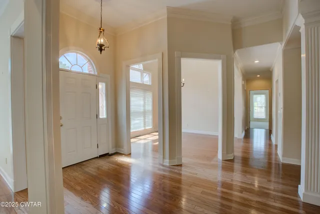 a view of a hallway with wooden floor and chandelier