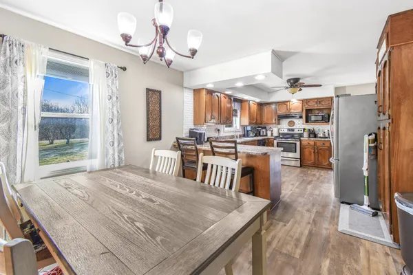 a open kitchen with stainless steel appliances granite countertop a stove refrigerator and a dining table with wooden floor