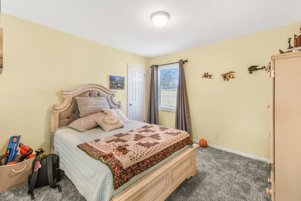 a bedroom with a bed and a dresser with wooden floor