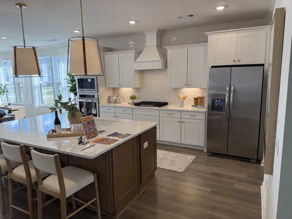 a kitchen with stainless steel appliances granite countertop a sink a stove a refrigerator cabinets and a dining table with wooden floor