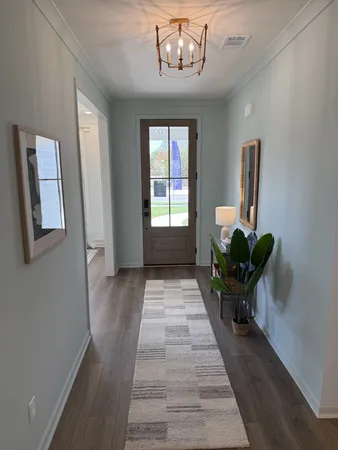 a view of a hallway with wooden floor and a chandelier