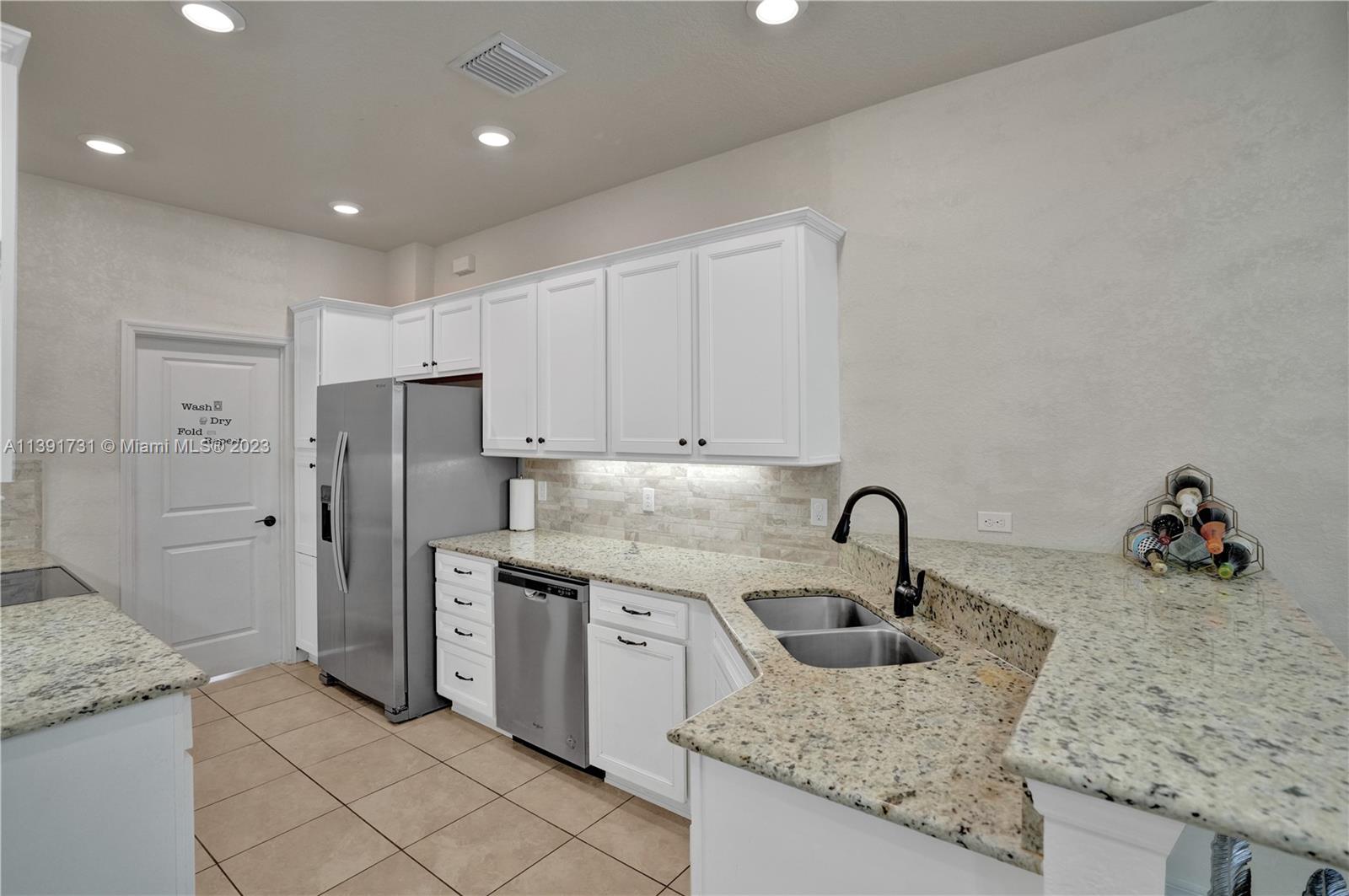 5060 Eucalyptus Drive, Unit 2 Hollywood, FL 33021 - Photo 12 of 56 a kitchen with stainless steel appliances granite countertop a sink and a refrigerator