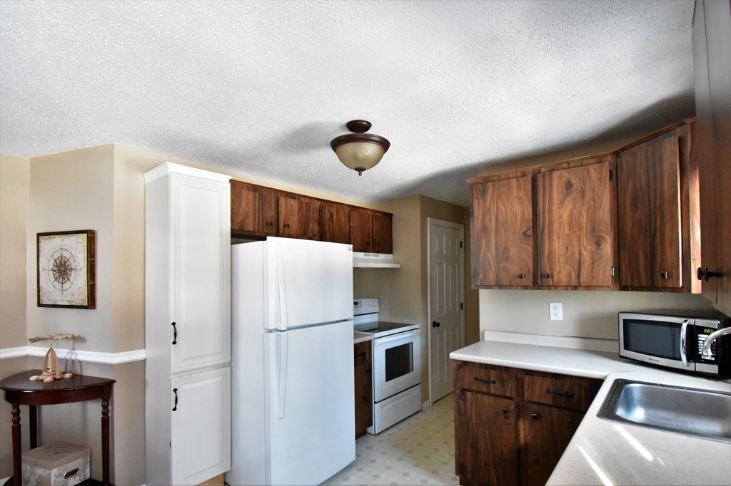 38 Juniper Road, Unit R Derry, NH 03038 - Photo 6 of 22 a kitchen with stainless steel appliances a refrigerator a stove a sink dishwasher and white cabinets with wooden floor